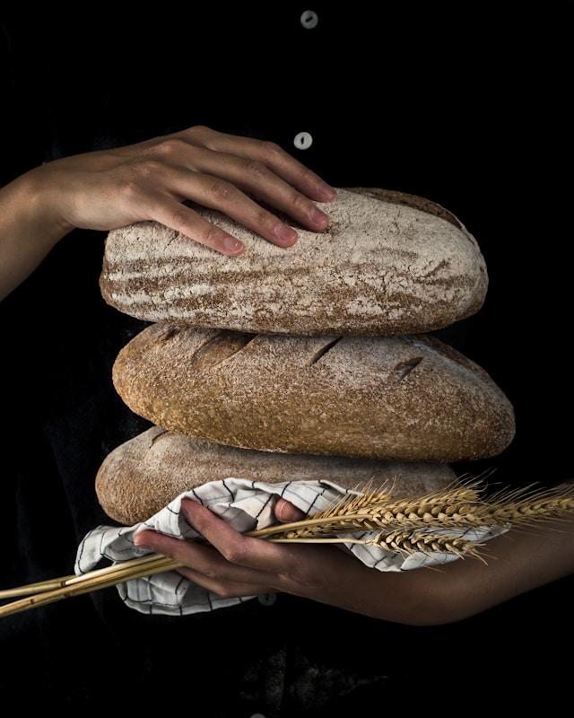 An individual presents a loaf of bread in one hand and a handful of wheat in the other, highlighting the essence of nourishment.